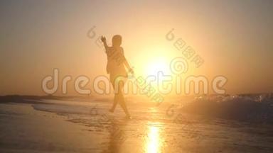 快乐的小女孩快乐地跳在靠近海边的海滩上，<strong>金色</strong>的夕阳上波涛汹涌。 高清，1920x1080。 慢动作。